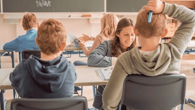 Lehrkraft begleitet Grundschulkinder beim gemeinsamen Lernen im Klassenzimmer.