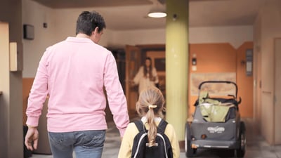 Vater begleitet seine Tochter mit Rucksack in eine Kindertageseinrichtung.