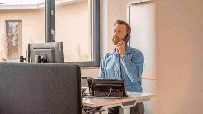 Mitarbeiter einer Kommunalverwaltung telefoniert an seinem Arbeitsplatz vor einem Computer.